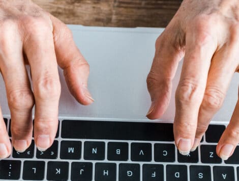 Senior hands typing on laptop